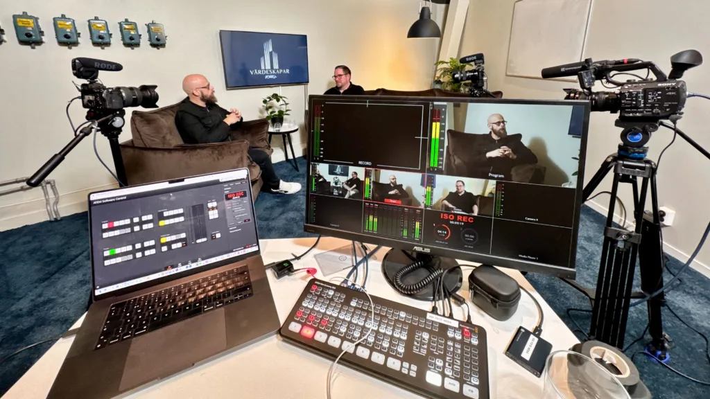 Professionell studioinspelning av en tittlyssna-podd med kameror, mikrofoner, videomixer och monitor för liveväxling mellan kameravinklar.